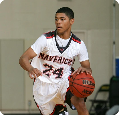 A basketball player in a white "Mavericks" jersey, number 24, dribbles the ball on a court. His focus and agility convey determination.